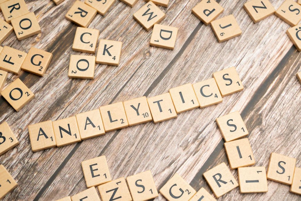 Scrabble tiles spelling 'Analytics' on a wooden surface, symbolizing data analytics concept.