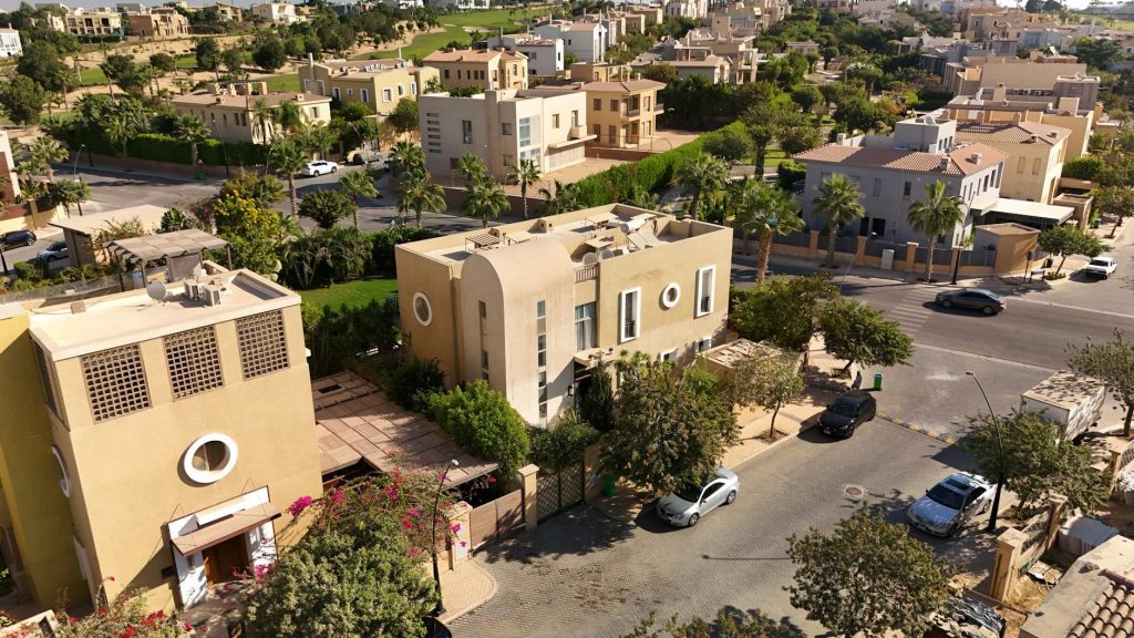 Aerial image showcasing modern villas and greenery in a luxury community in West Cairo, Egypt, perfect for real estate insights.