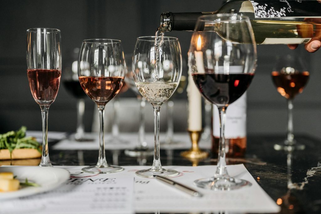 Elegant wine tasting setup with various wines being poured into glasses indoors.