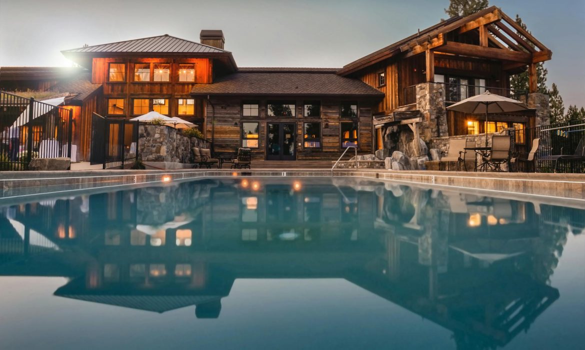 Stunning wooden villa with a large pool and cozy lights, perfect for a luxurious escape.