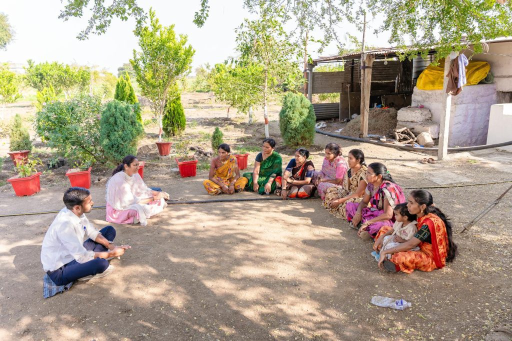 A diverse group gathered for a community meeting in rural Nagpur, India, discussing agriculture.